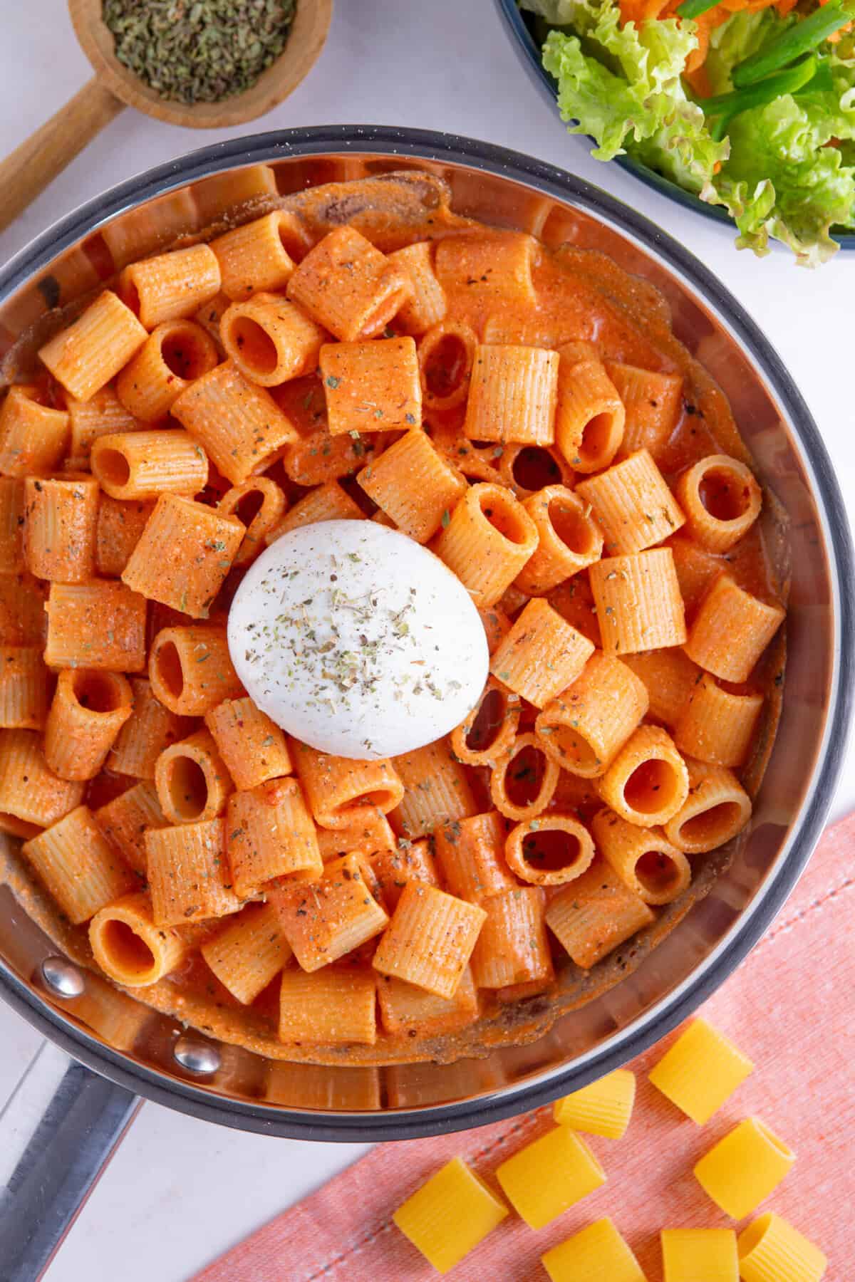 Process shot of tomato burrata pasta recipe showing the finished dish with a burrata ball on top.