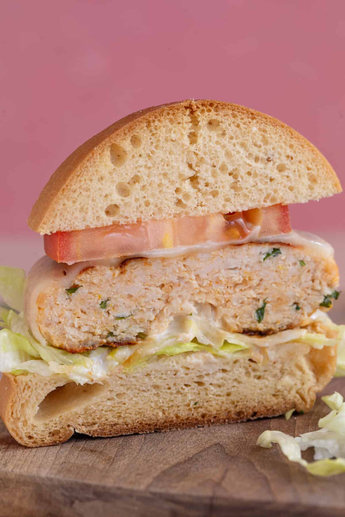 Cross section of a gluten free chicken burger in a bun cut in half.