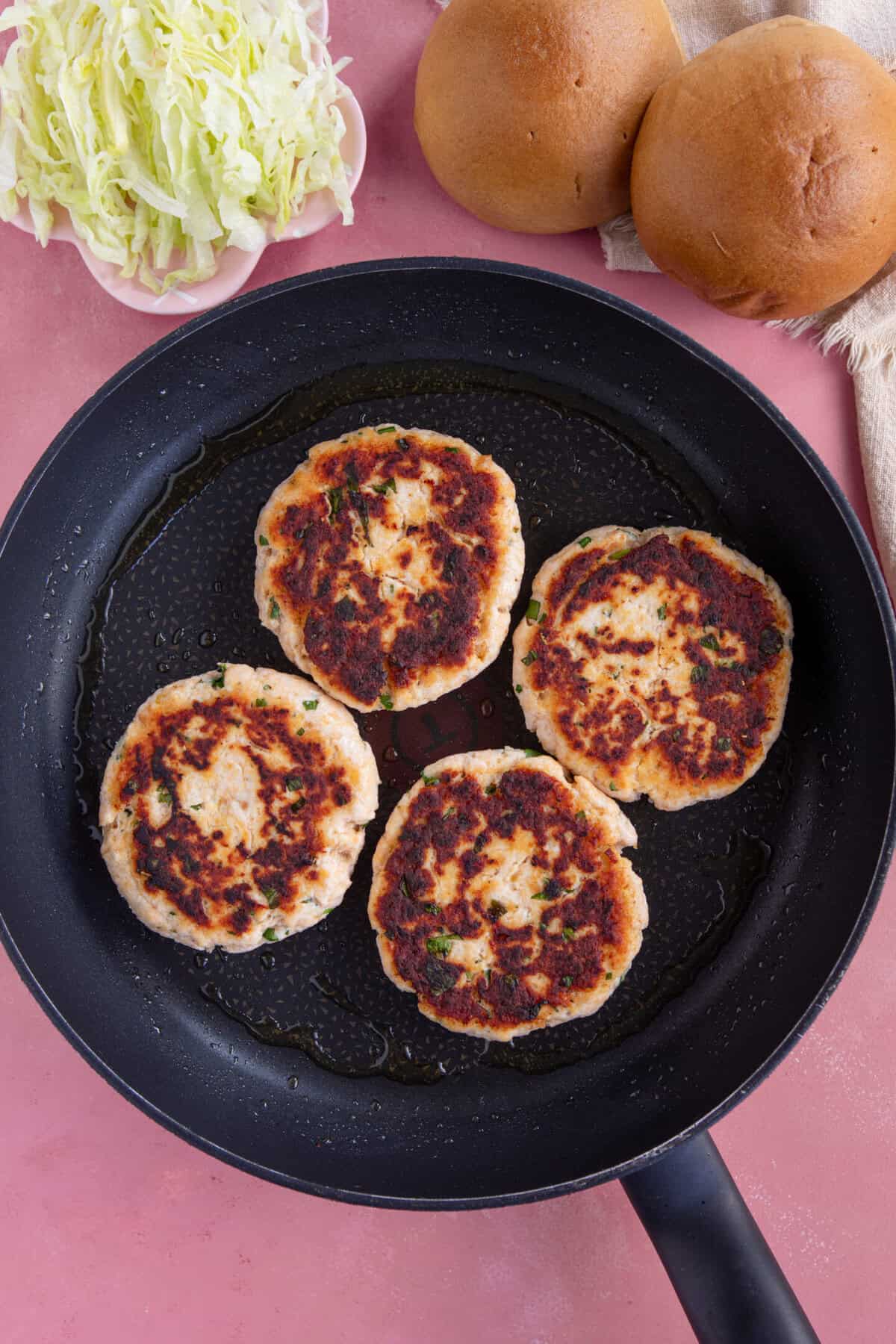 Process shot for chicken mince burgers showing the cooked chicken burger patties in a pan.