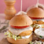 Gluten free chicken burgers on a board with cheese a tomato slice.