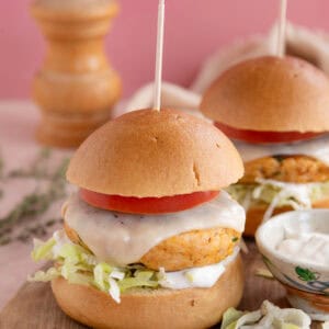 Gluten free chicken burgers on a board with cheese a tomato slice.