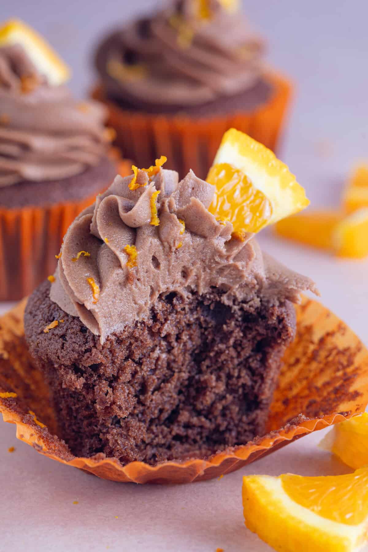 A gluten free chocolate orange cupcake with a bite taken out of it.
