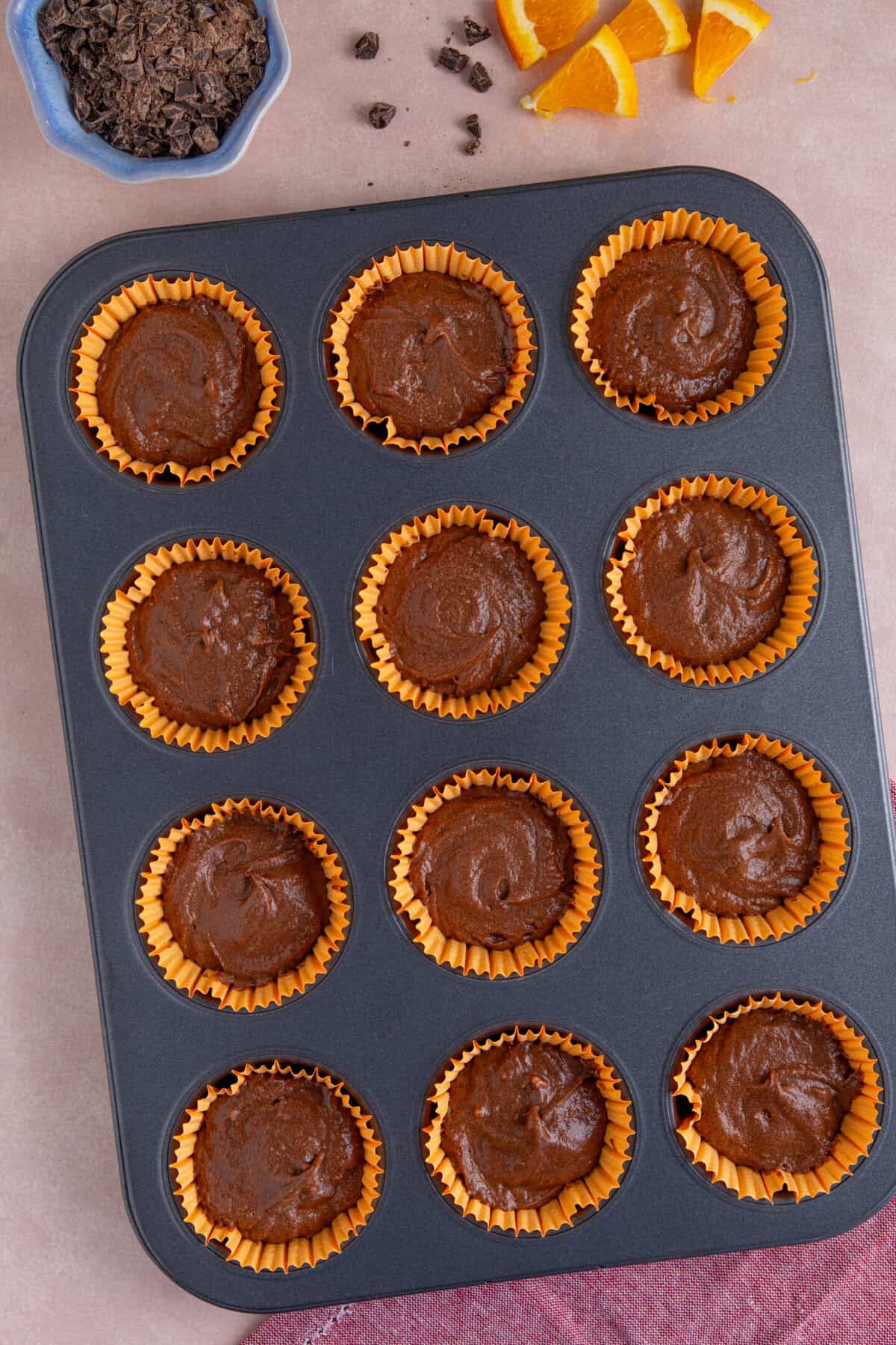 Process shot of gluten free chocolate orange cupcakes showing the cupcake batter in the tin ready to bake.