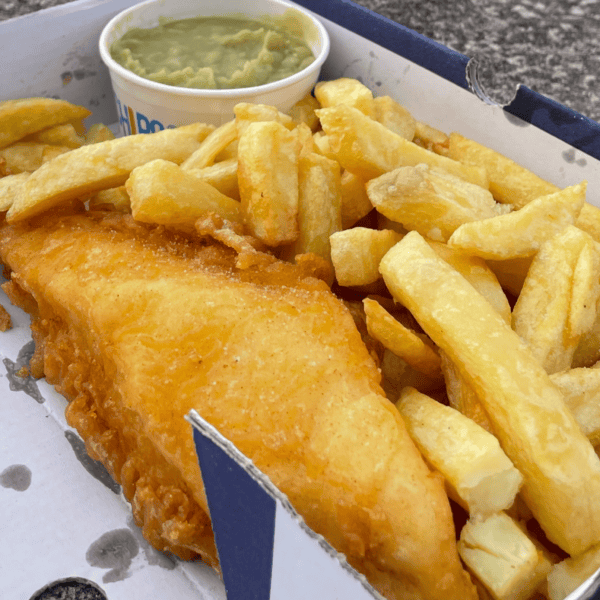Gluten free fish, chips and mushy peas on a rock by the sea.