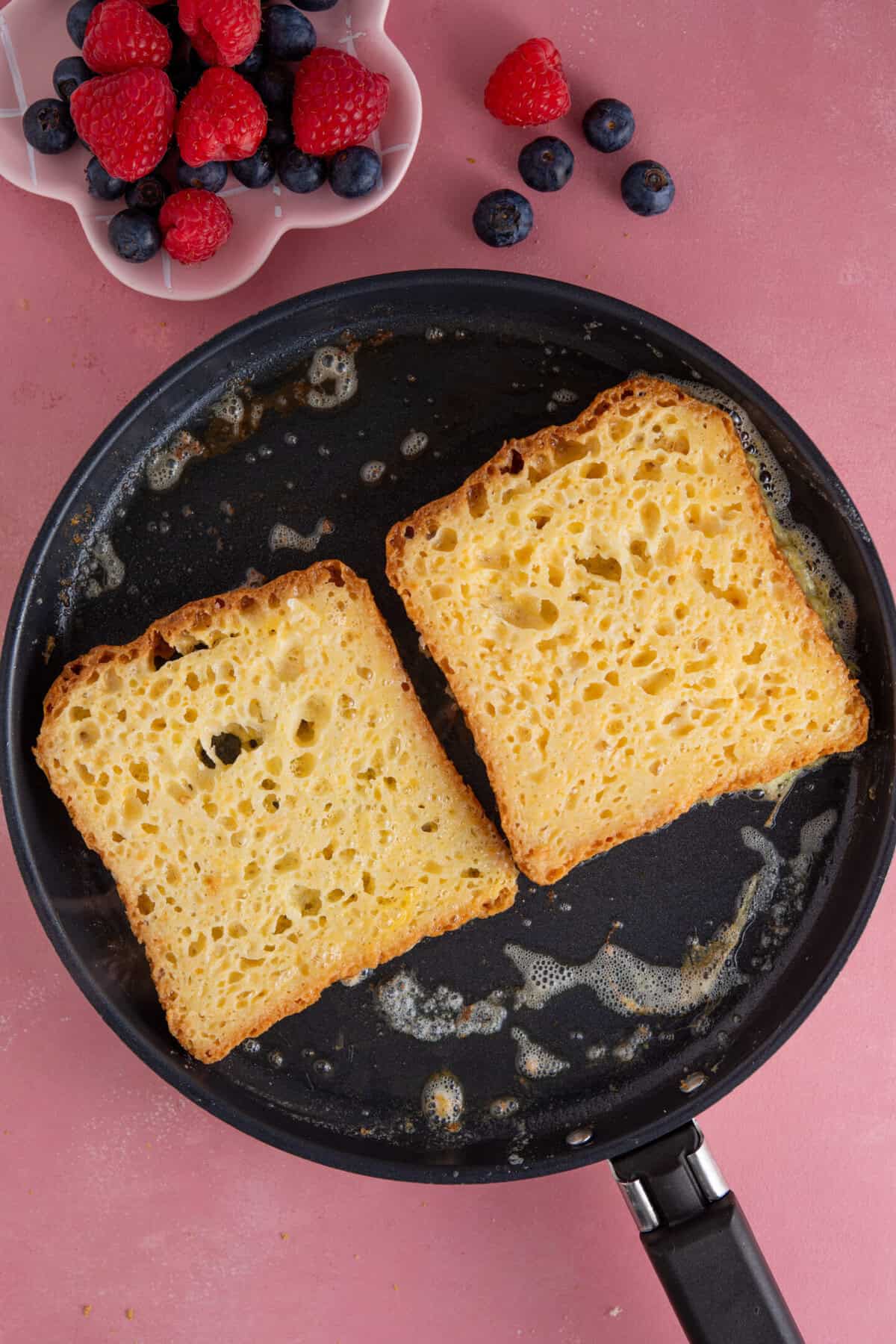 Process shot of gluten free French toast showing the eggy bread slices frying in a pan.