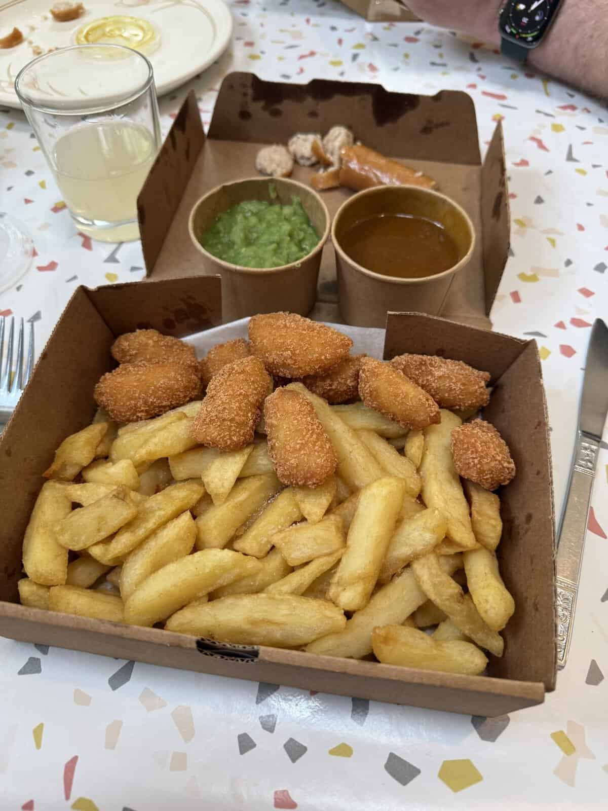 A box of gluten free scampi, chips and mushy peas with curry sauce.