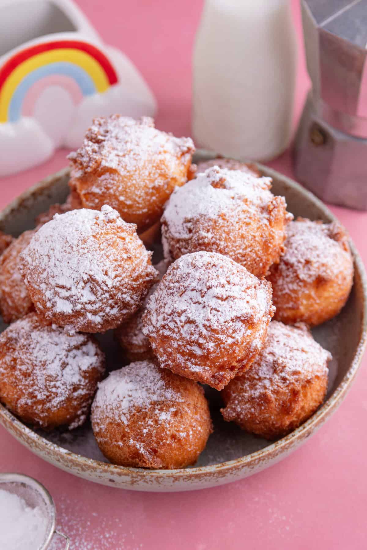 A bowl of gluten free zeppole dusted with icing sugar.