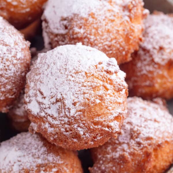 Close up of gluten free zeppole - fried doughnut balls dusted in icing sugar.