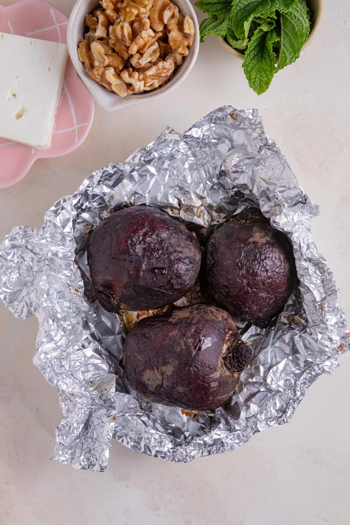 Process shot of beetroot salad recipe showing beetroot roasted in foil.
