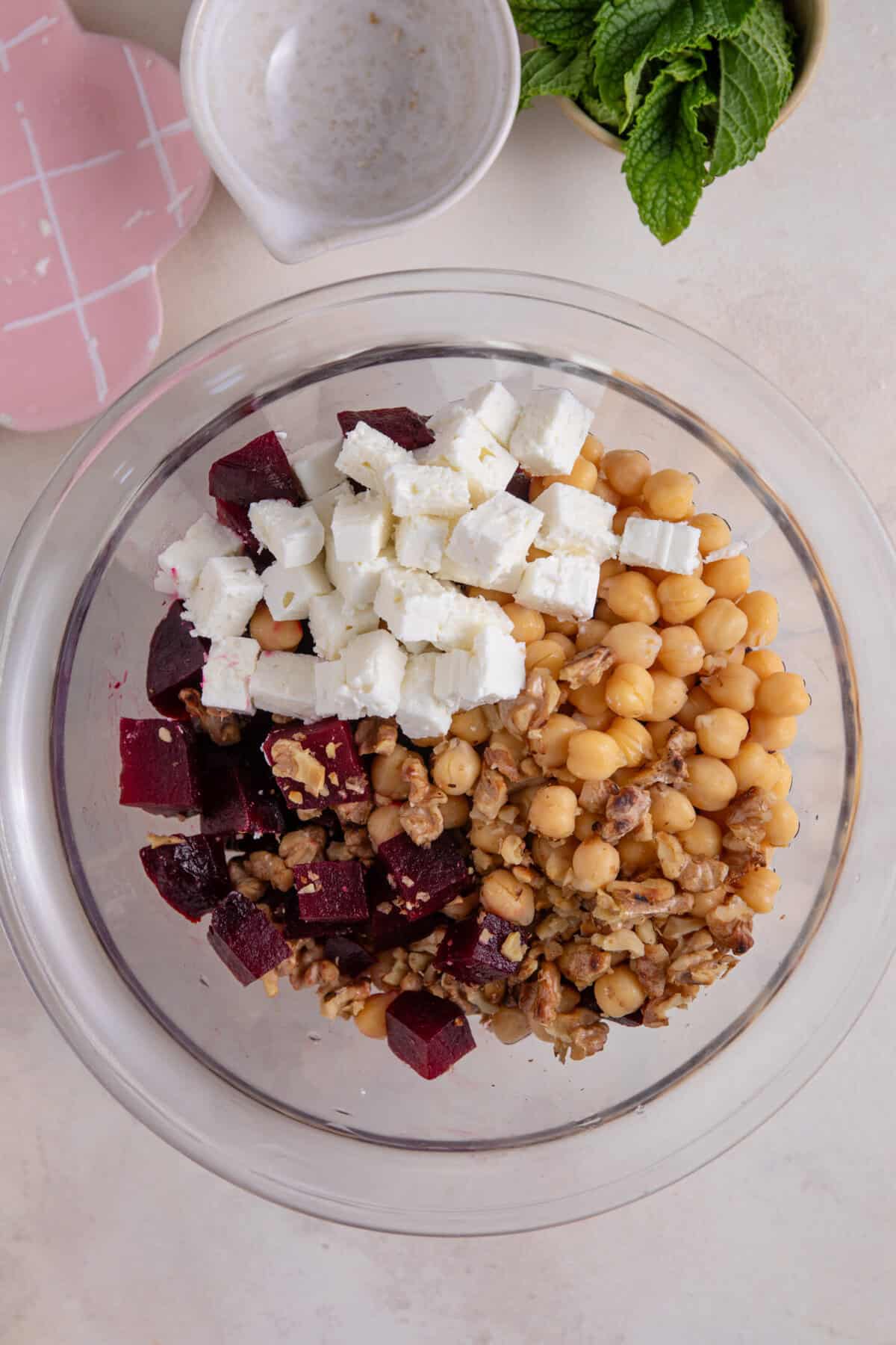 Process shot of beetroot salad recipe showing all the ingredients into a large glass bowl.