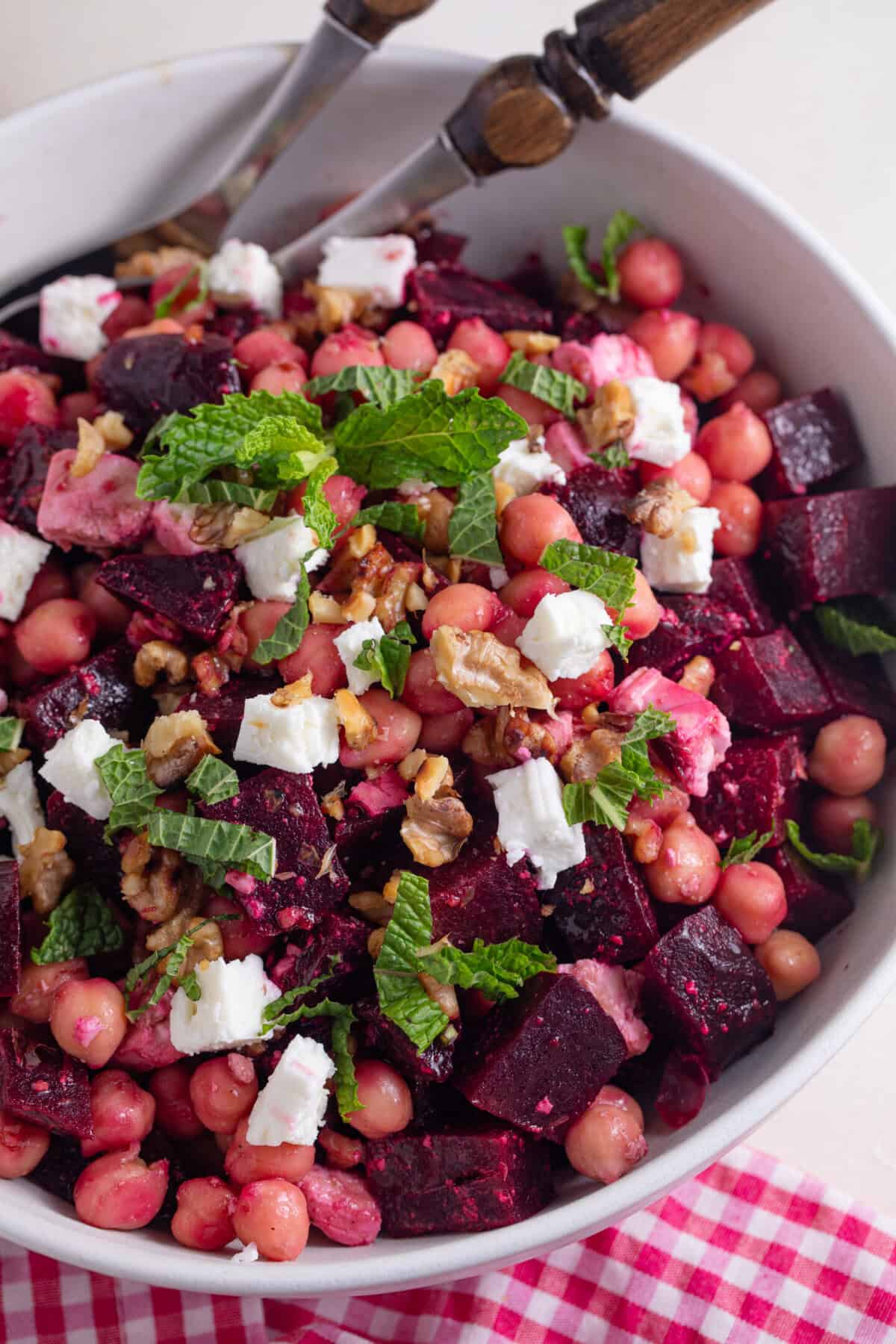 A bowl of beetroot salad with feta, chickpeas, olive and fresh mint on top.