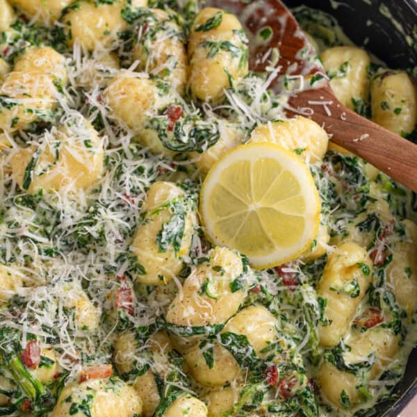 Close up of creamy gnocchi with spinach and bacon in a pan.