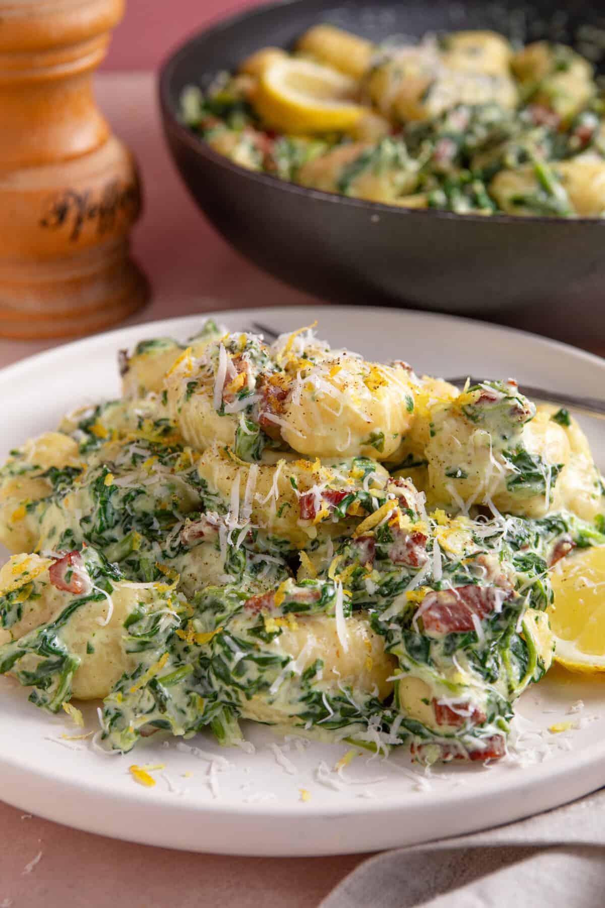 A plate of creamy, gluten free gnocchi with spinach and bacon.