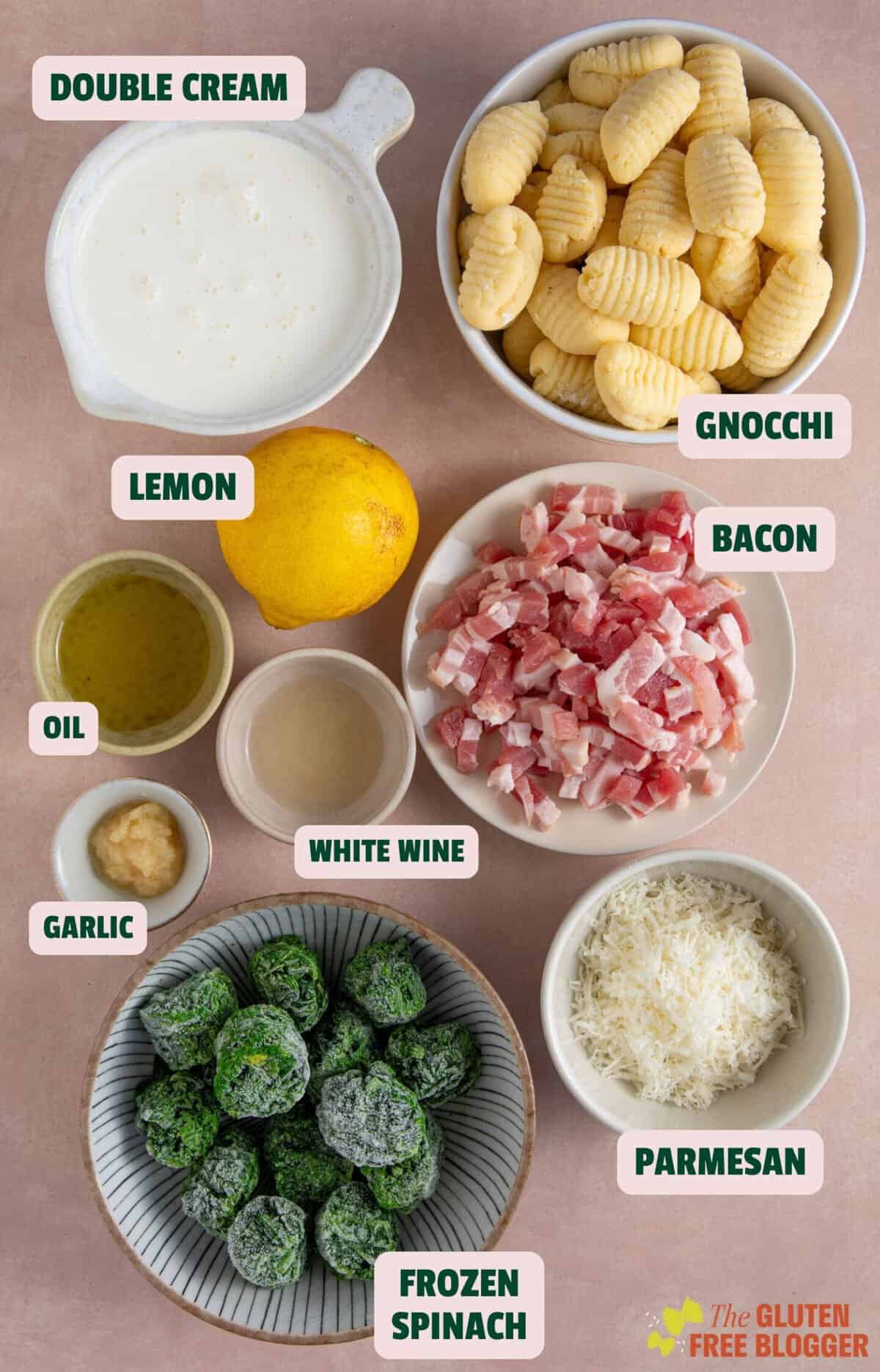 Flat lay of ingredients for creamy gnocchi recipe including bacon, spinach, cream, gnocchi and lemon.