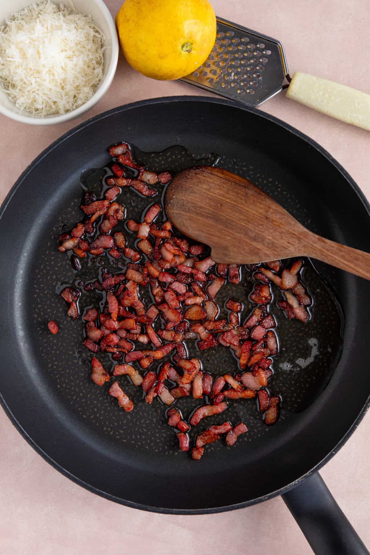 Process shot of creamy gnocchi recipe showing the bacon lardons frying in a pan.