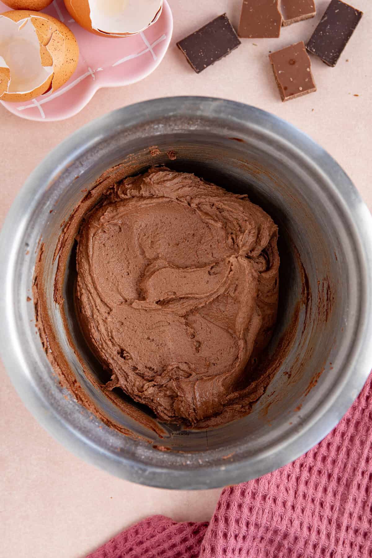Process shot of a gluten free chocolate loaf cake recipe showing the chocolate buttercream in a metal bowl.