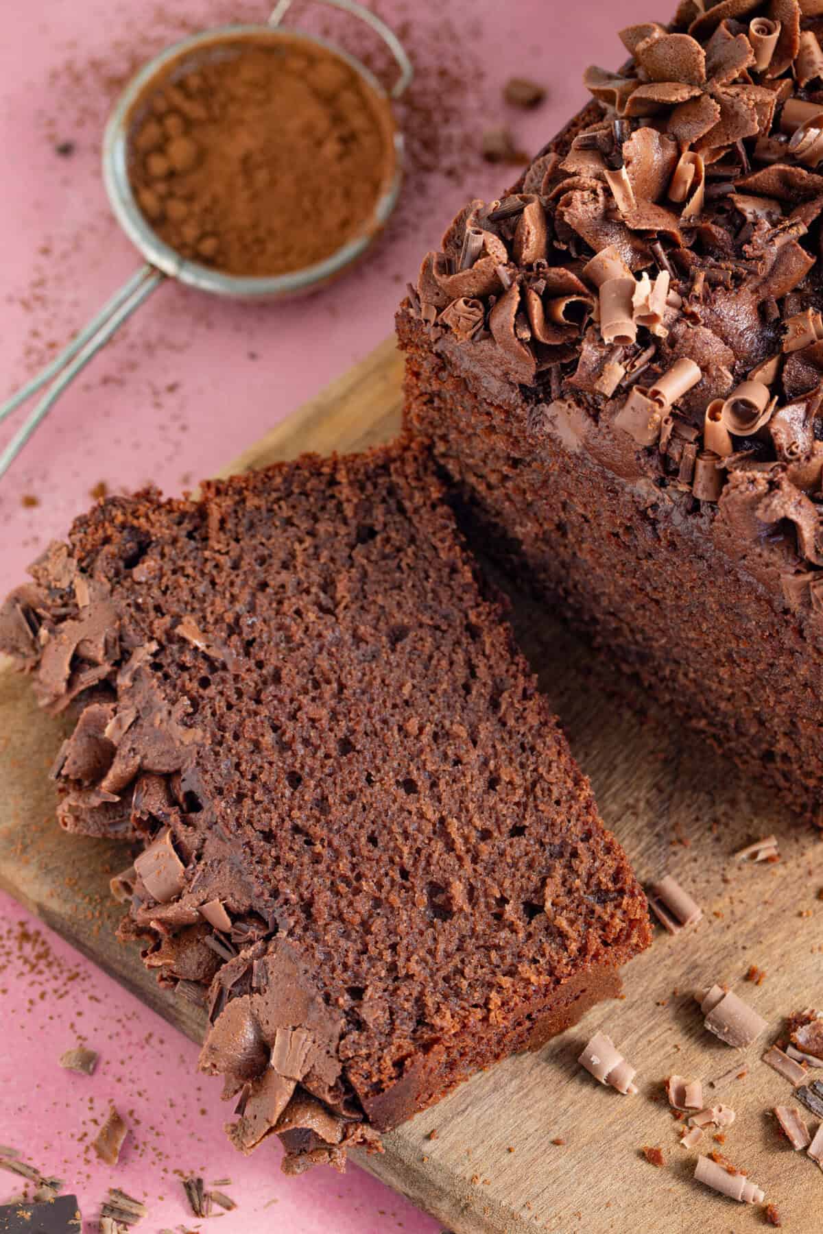 A slice of gluten free chocolate loaf cake on a wooden board.