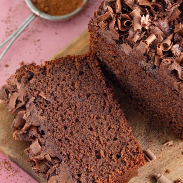 A slice of gluten free chocolate loaf cake on a wooden board.