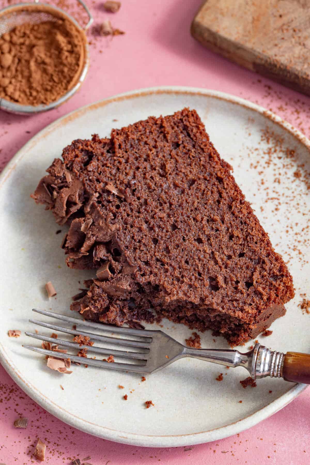 A slice of gluten free chocolate loaf cake on a plate with a forkful taken away.