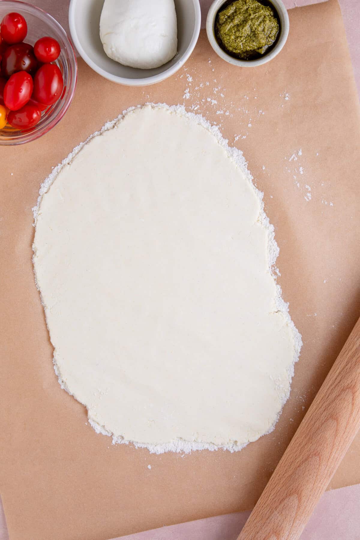 Process shot of gluten free flatbread pizza recipe showing the dough rolled into an oval shape on baking paper.