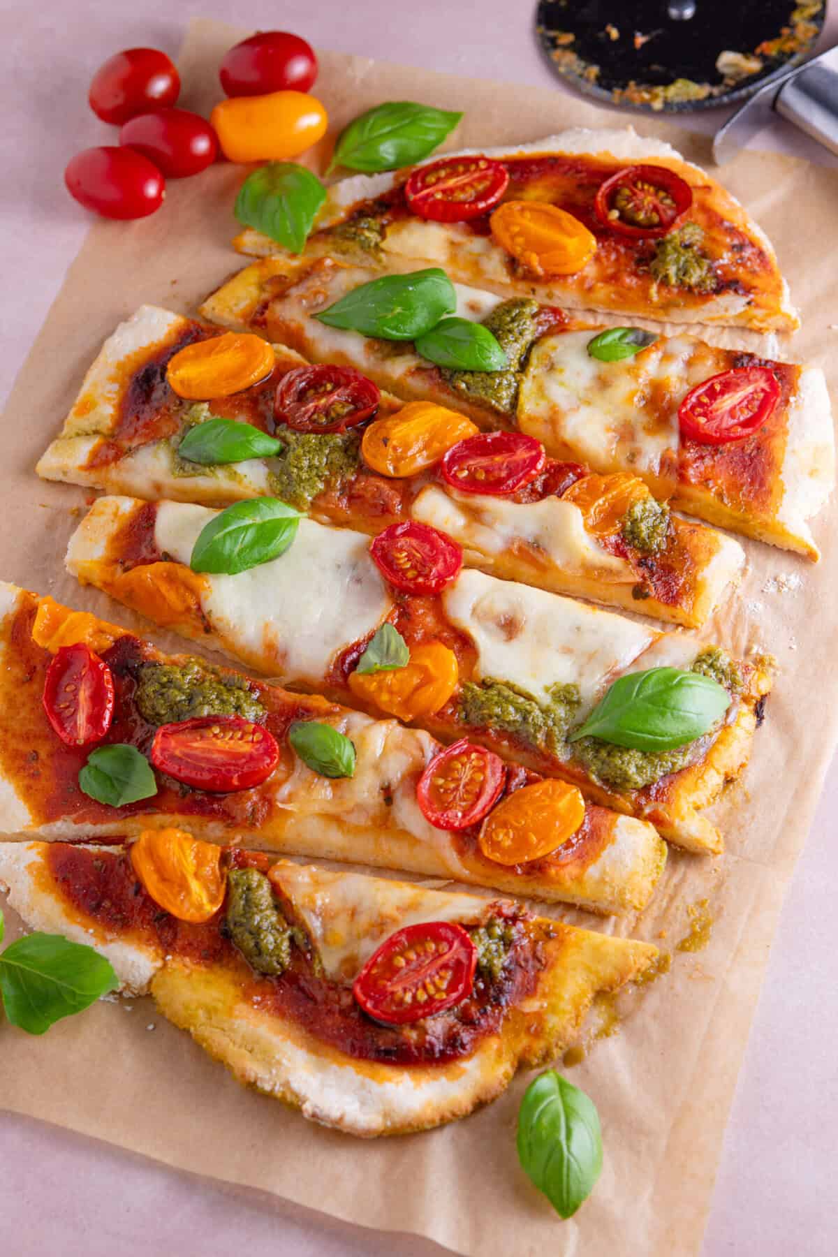 Gluten free flatbread pizza topped with tomato, pesto and basil and cut into strips.