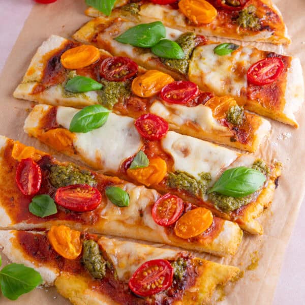Gluten free flatbread pizza topped with tomato, pesto and basil and cut into strips.