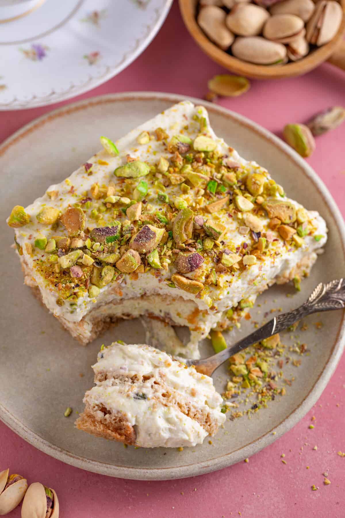 A plate of gluten free pistachio tiramisu with a bite taken out.