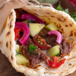 A gluten free kebab made with the viral sheet pan kebab, a gluten free flatbread, cucumber, red onion and tomatoes.