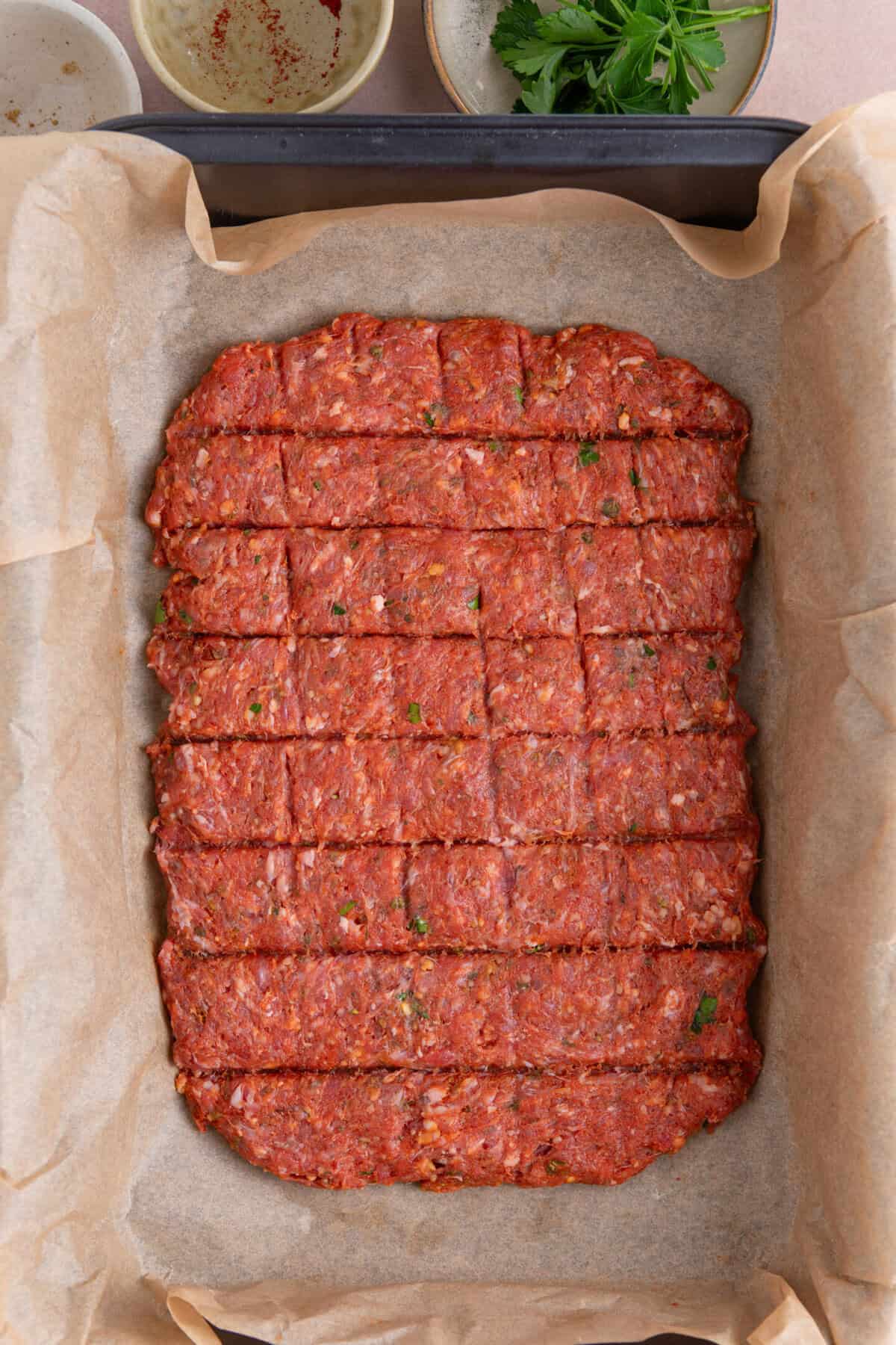 Process shot for sheet pan kebabs recipe showing the mixture on a baking sheet with indentations on top, ready to cook.