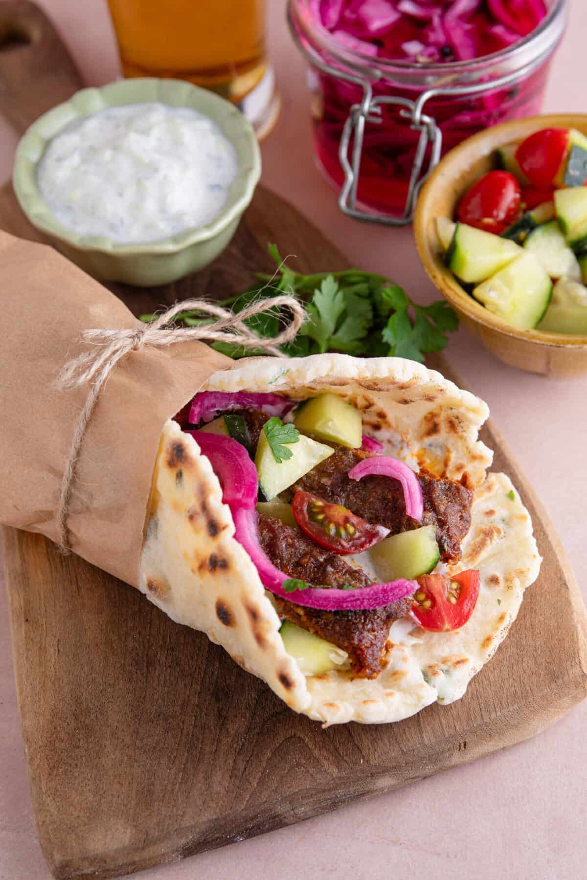 A gluten free kebab made with the viral sheet pan kebab, a gluten free flatbread, cucumber, red onion and tomatoes.