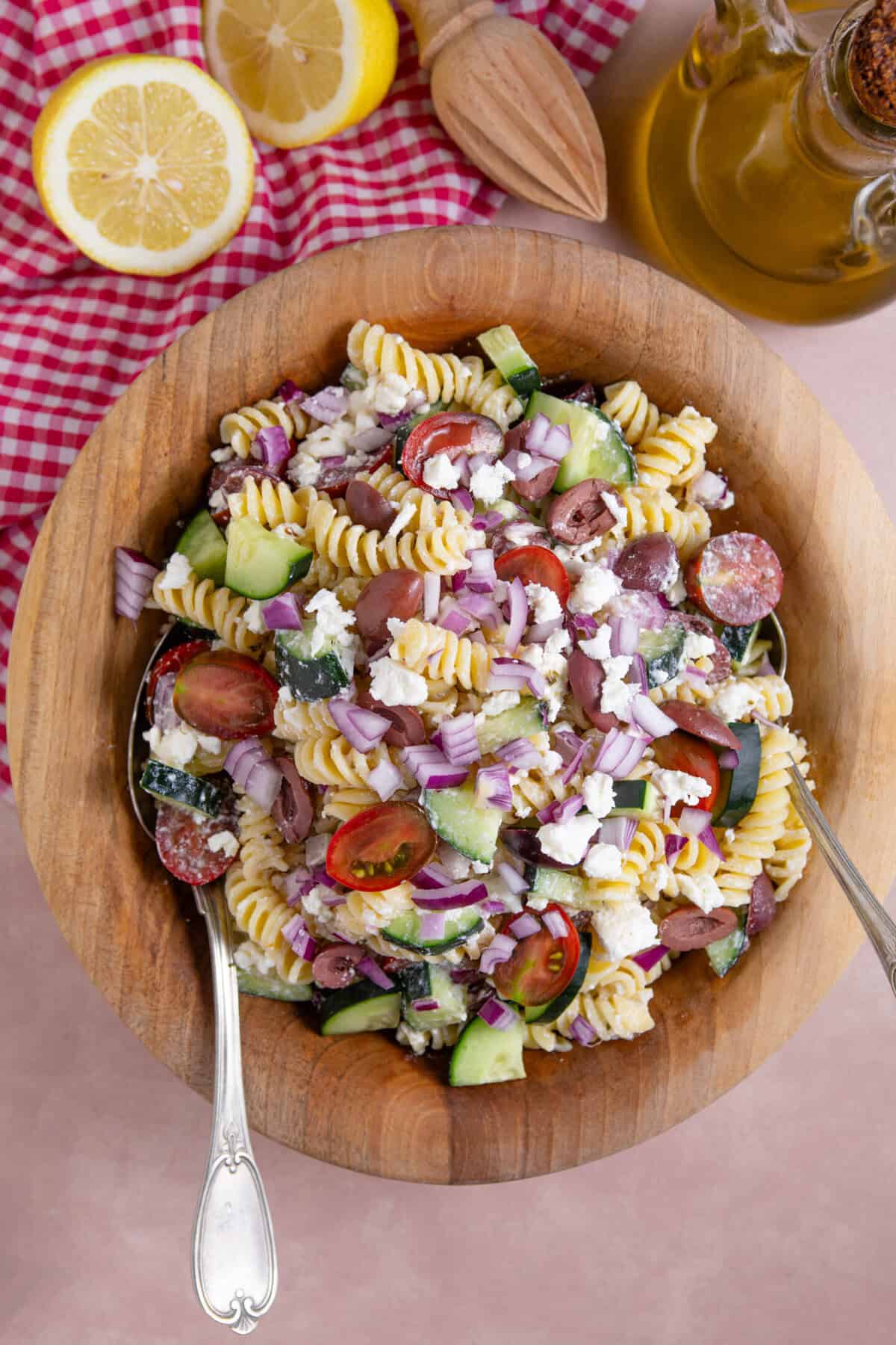 A a bowl of Greek Pasta salad with red onions, olives, feta, tomato and cucumber.