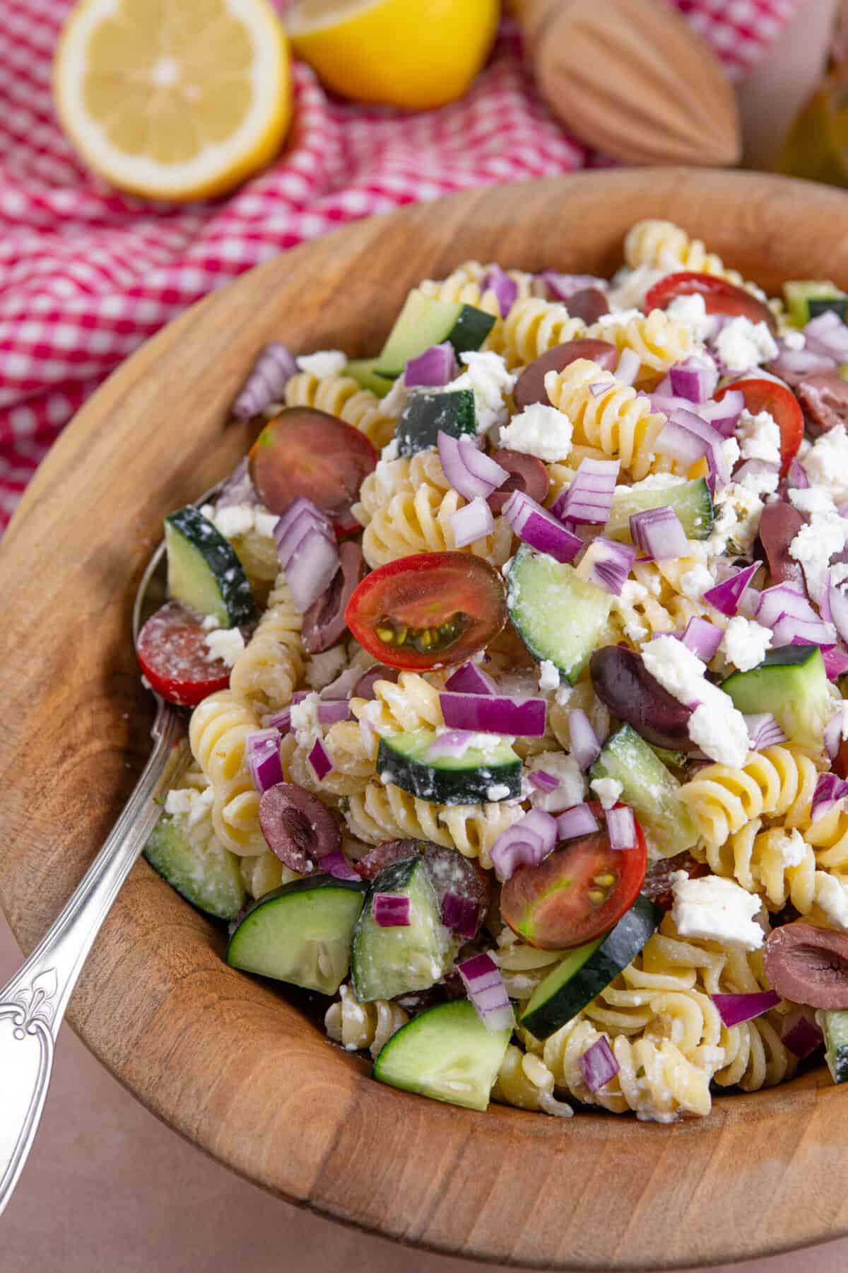 Close up of a bowl of Greek Pasta salad with red onions, olives, feta, tomato and cucumber.