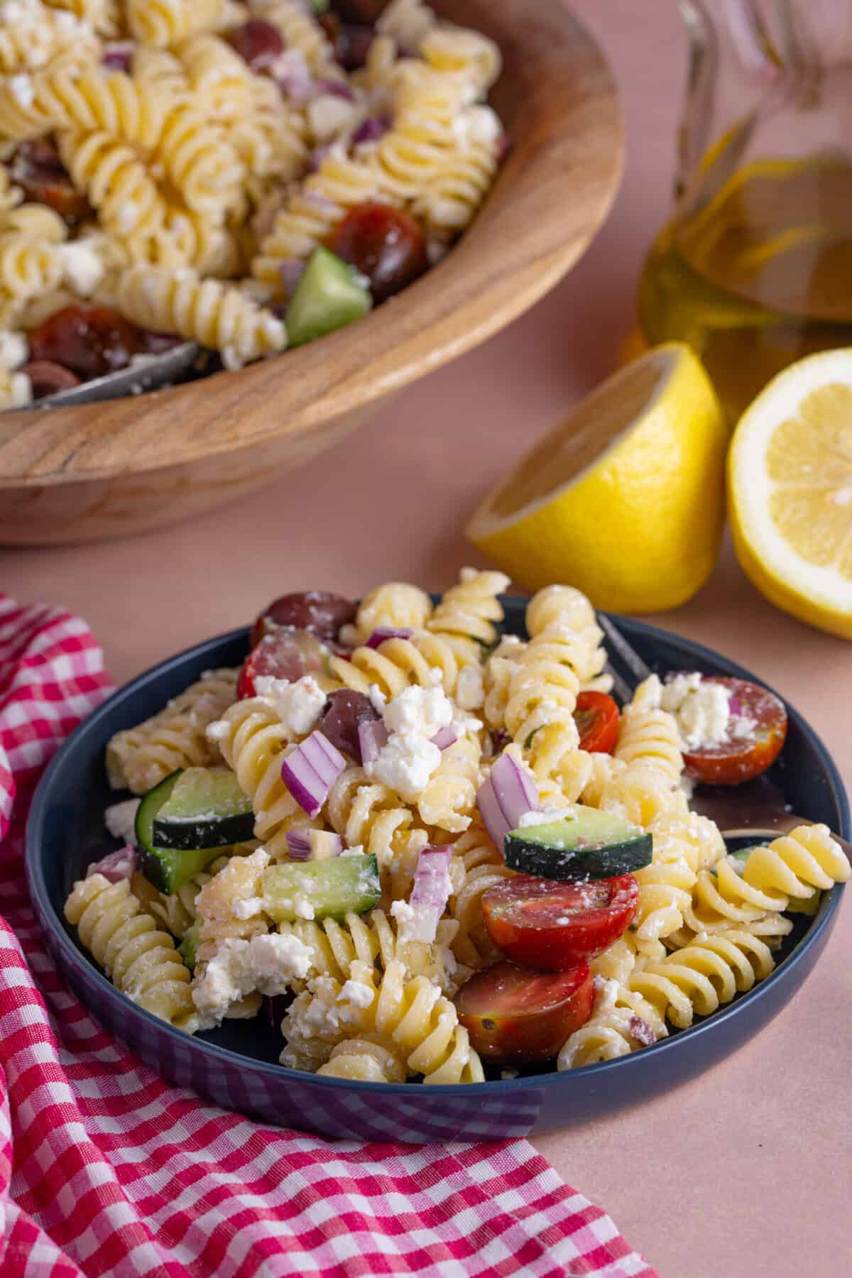 Close up of a bowl of Greek Pasta salad with red onions, olives, feta, tomato and cucumber.