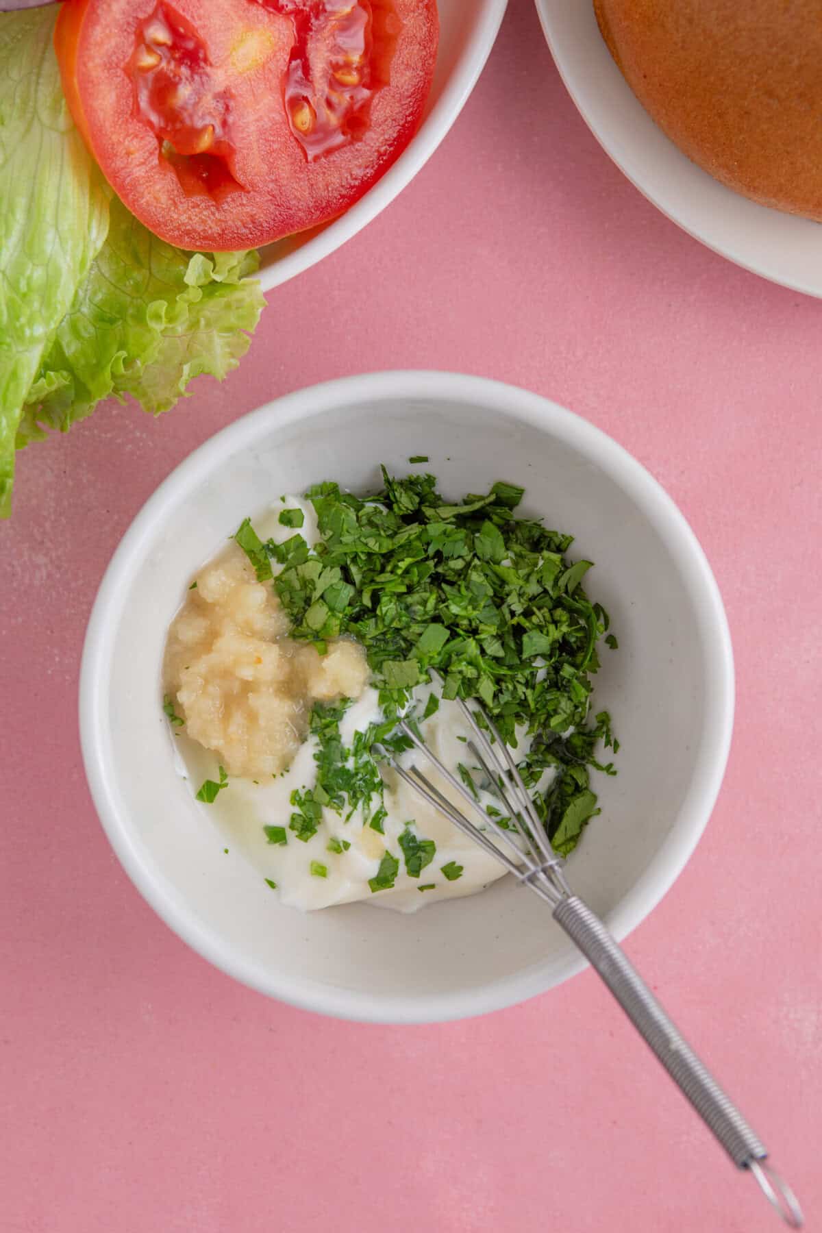 Process shot of gluten free halloumi burgers showing mixing together the lime and coriander mayo.