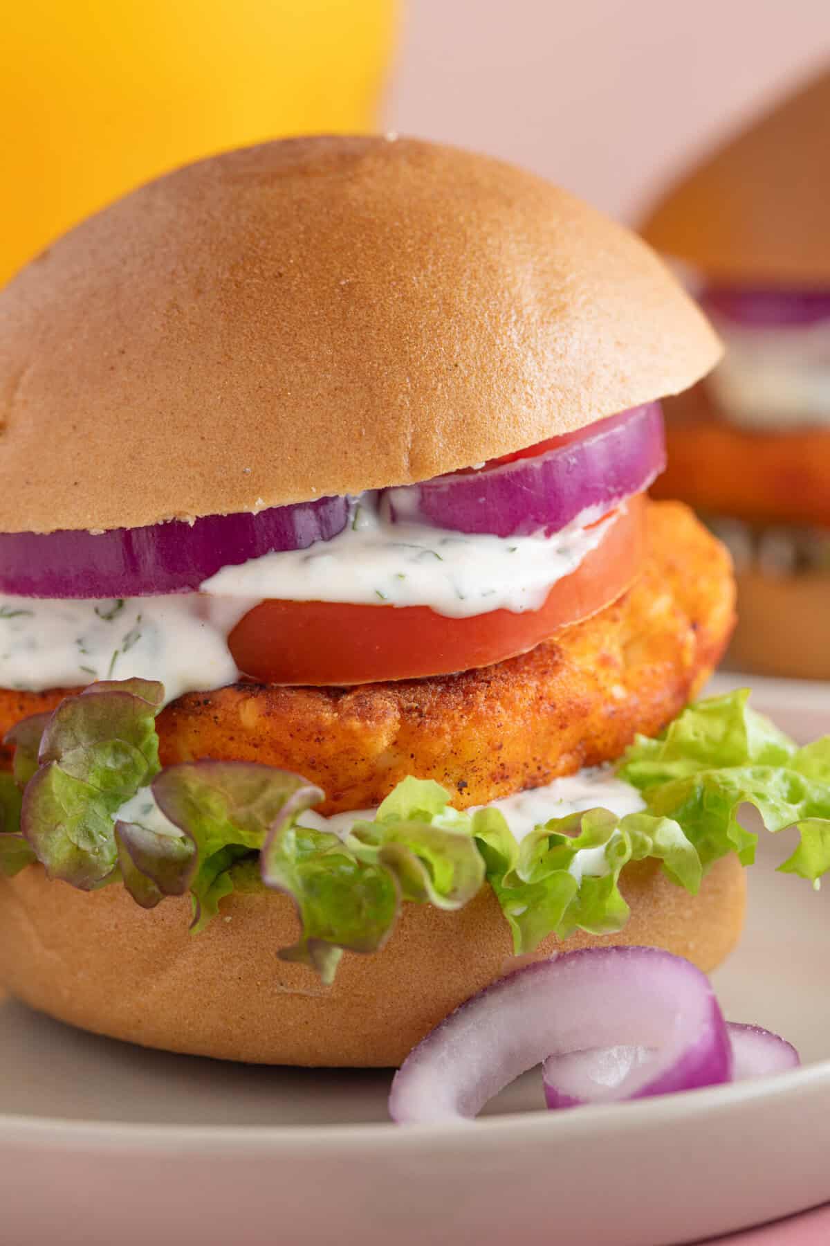 Close up shot of a crispy halloumi burger with red onion, salad, lime mayo and a burger bun.