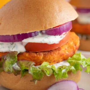 Close up shot of a crispy halloumi burger with red onion, salad, lime mayo and a burger bun.