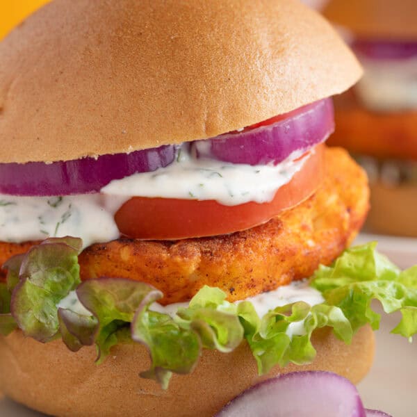 Close up shot of a crispy halloumi burger with red onion, salad, lime mayo and a burger bun.