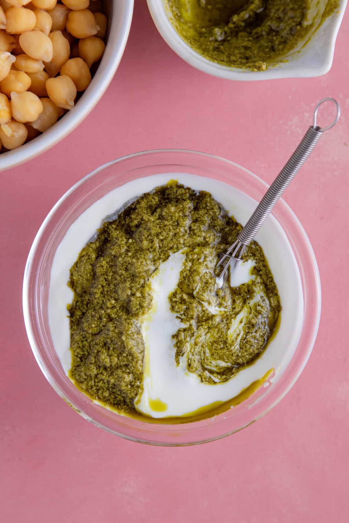 Process shot of gluten free pesto pasta salad recipe showing the yoghurt and pesto in a bowl before mixing.