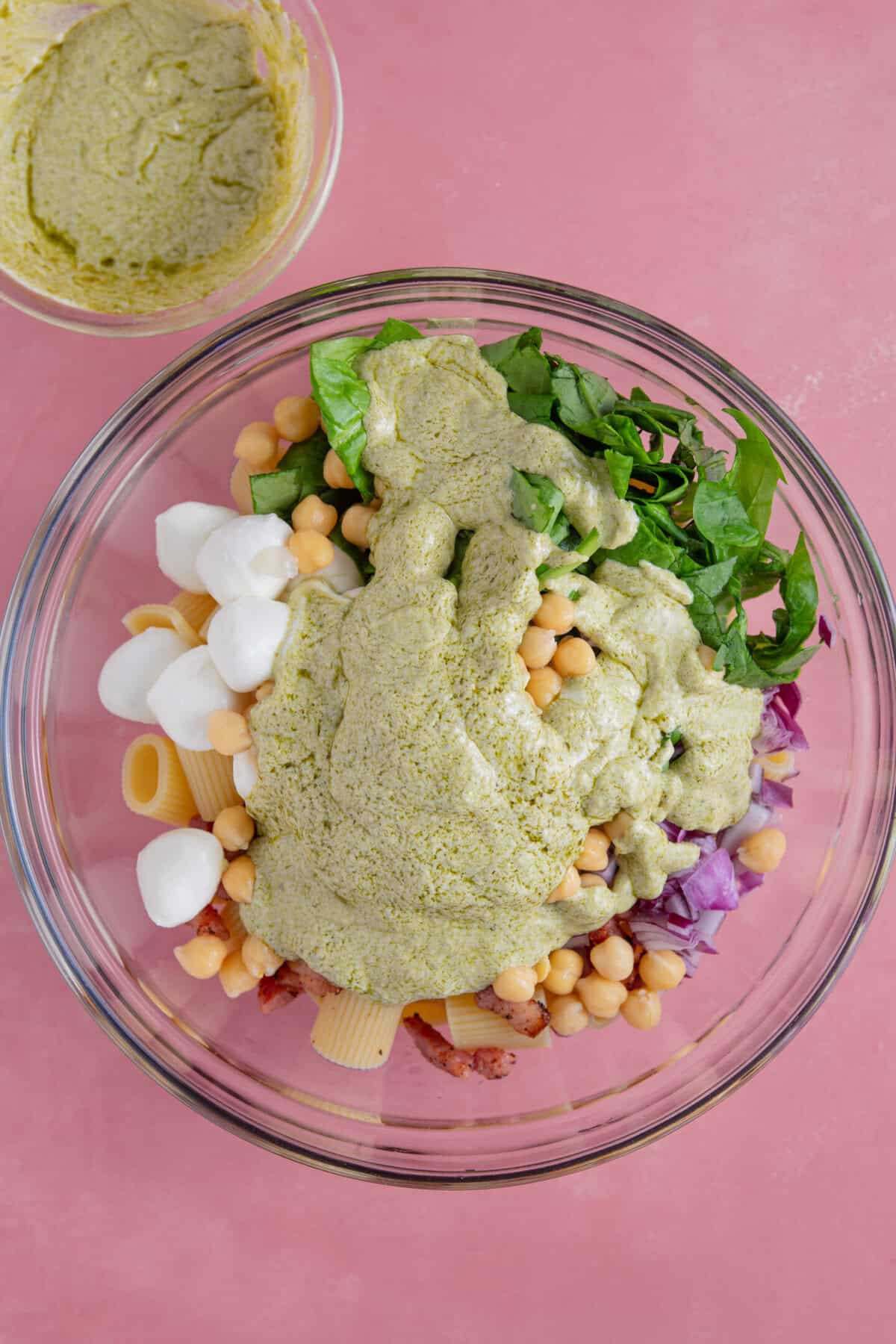 Process shot of gluten free pesto pasta salad recipe showing all the ingredients and sauce in a bowl before mixing.