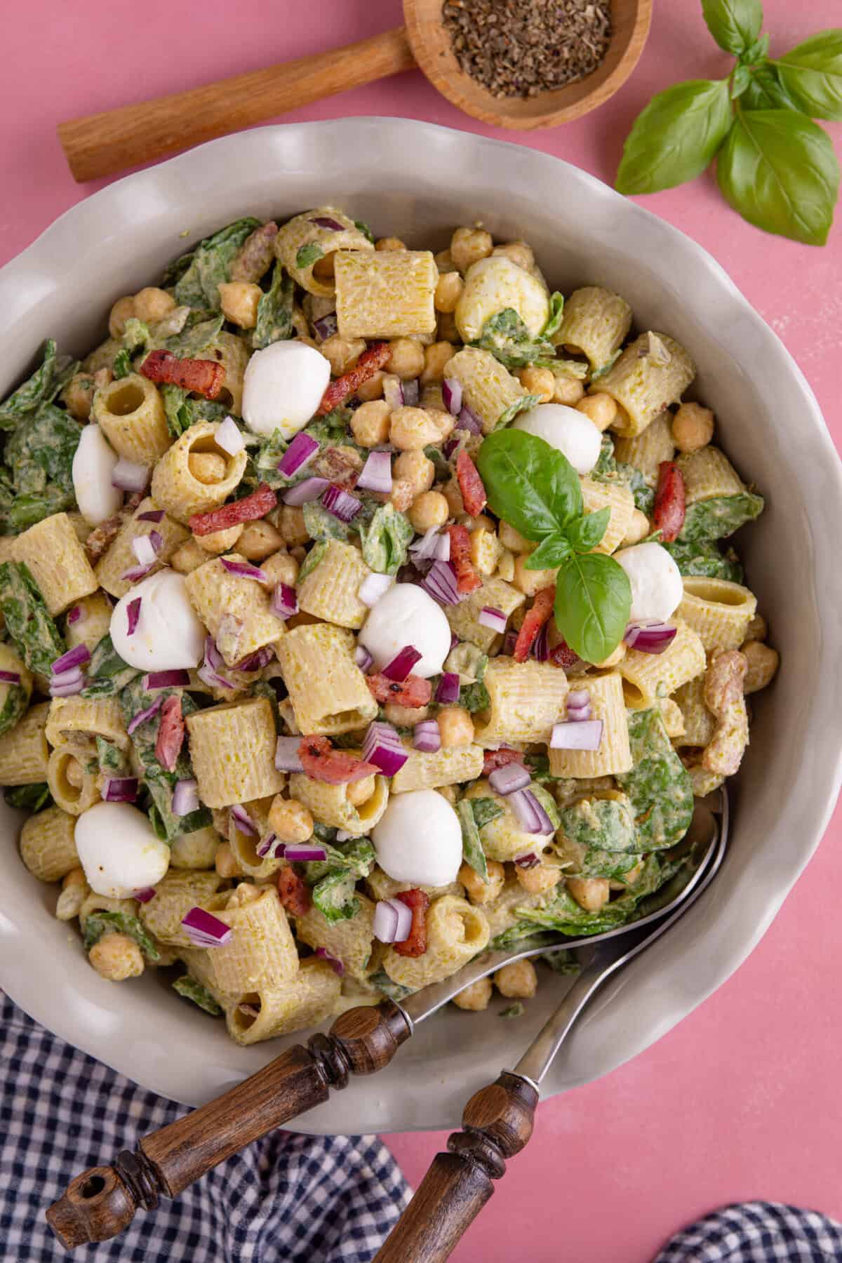 Process shot of gluten free pesto pasta salad recipe showing the finished pasta salad in a serving dish.