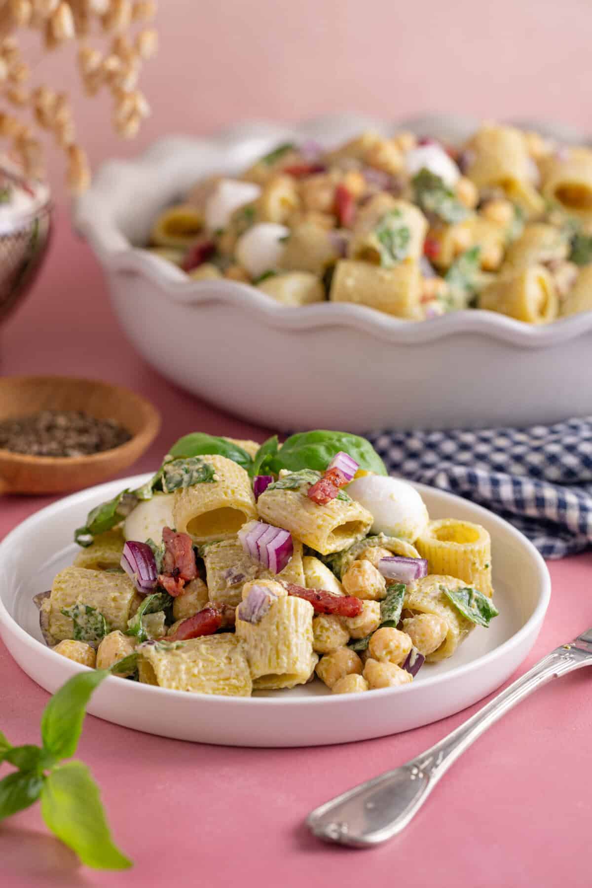 A gluten free pesto pasta salad with bacon, spinach and red onion.