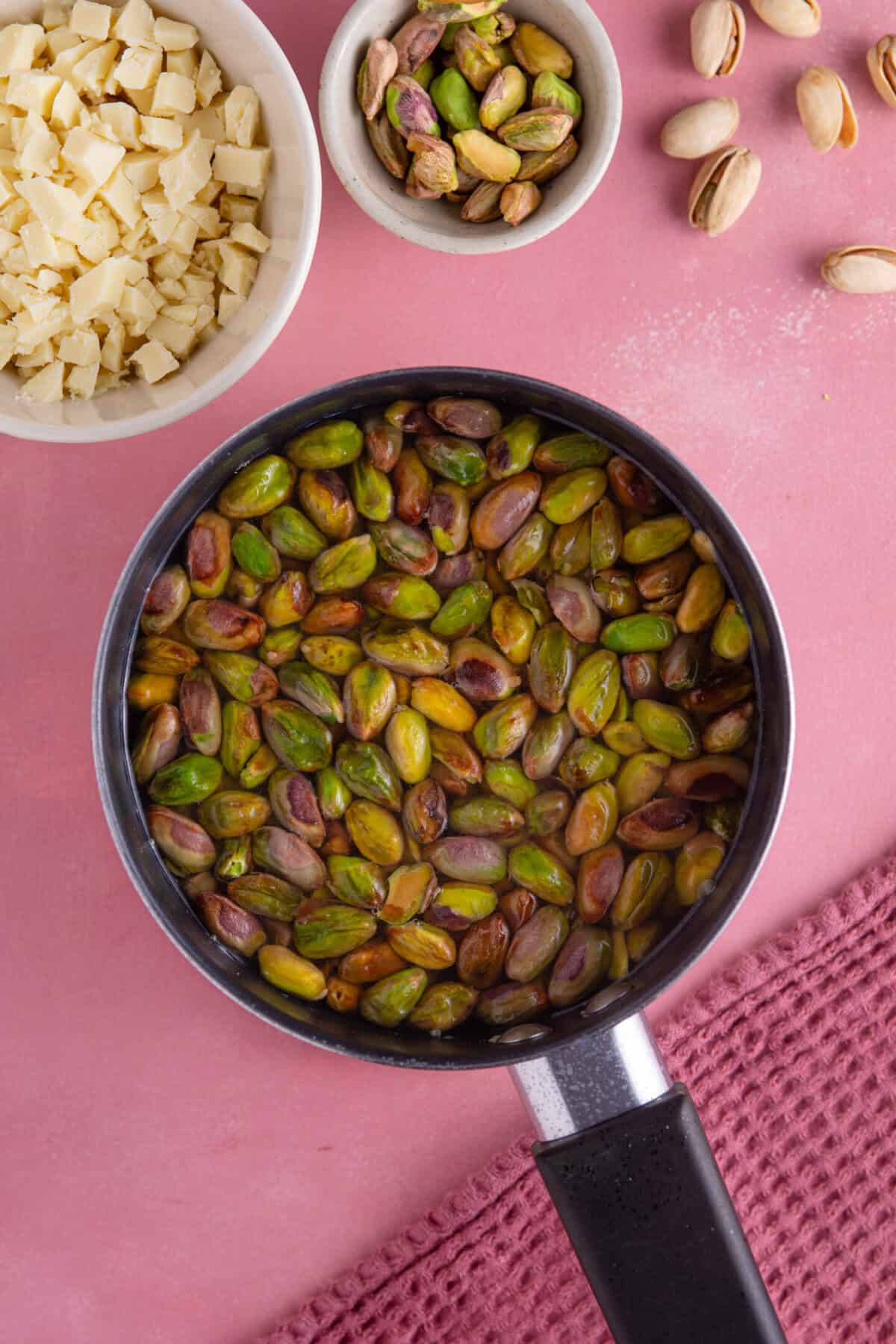 Process shot for pistachio spread recipe showing a pan full of water and pistachio kernels.