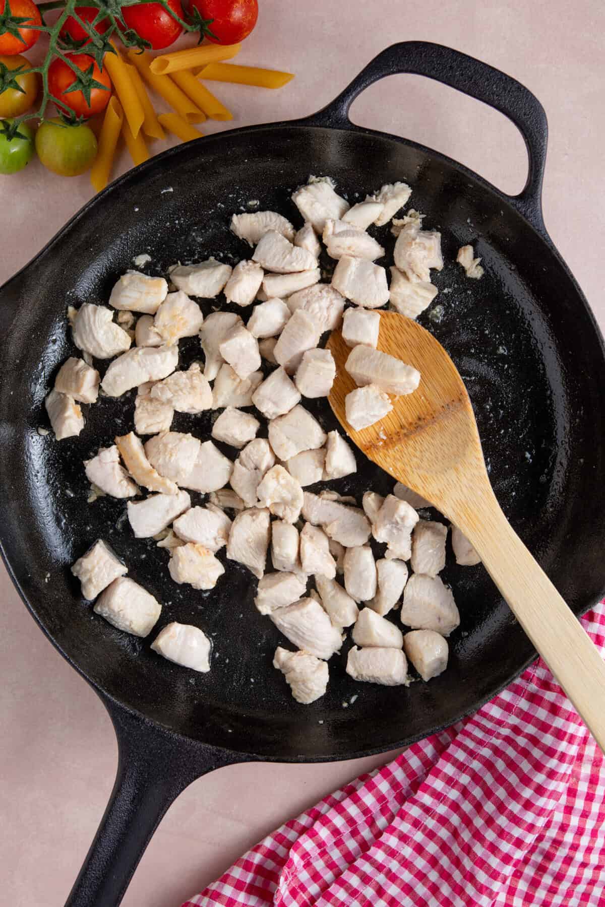 Process shot of creamy chicken tomato recipe showing the chicken chunks frying in a pan.
