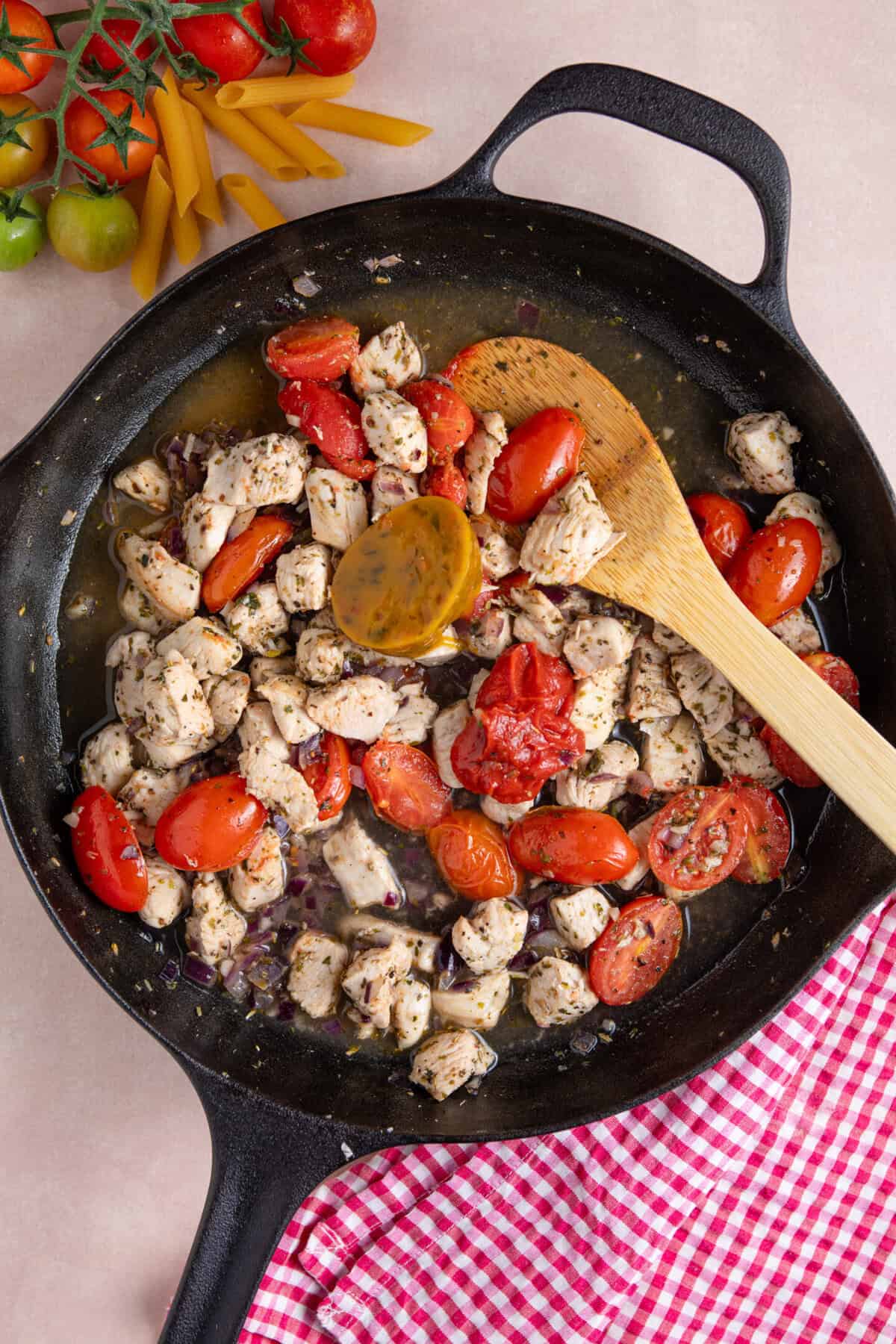 Process shot of creamy chicken tomato recipe showing the stock pot added to the chicken and veg in a pan.