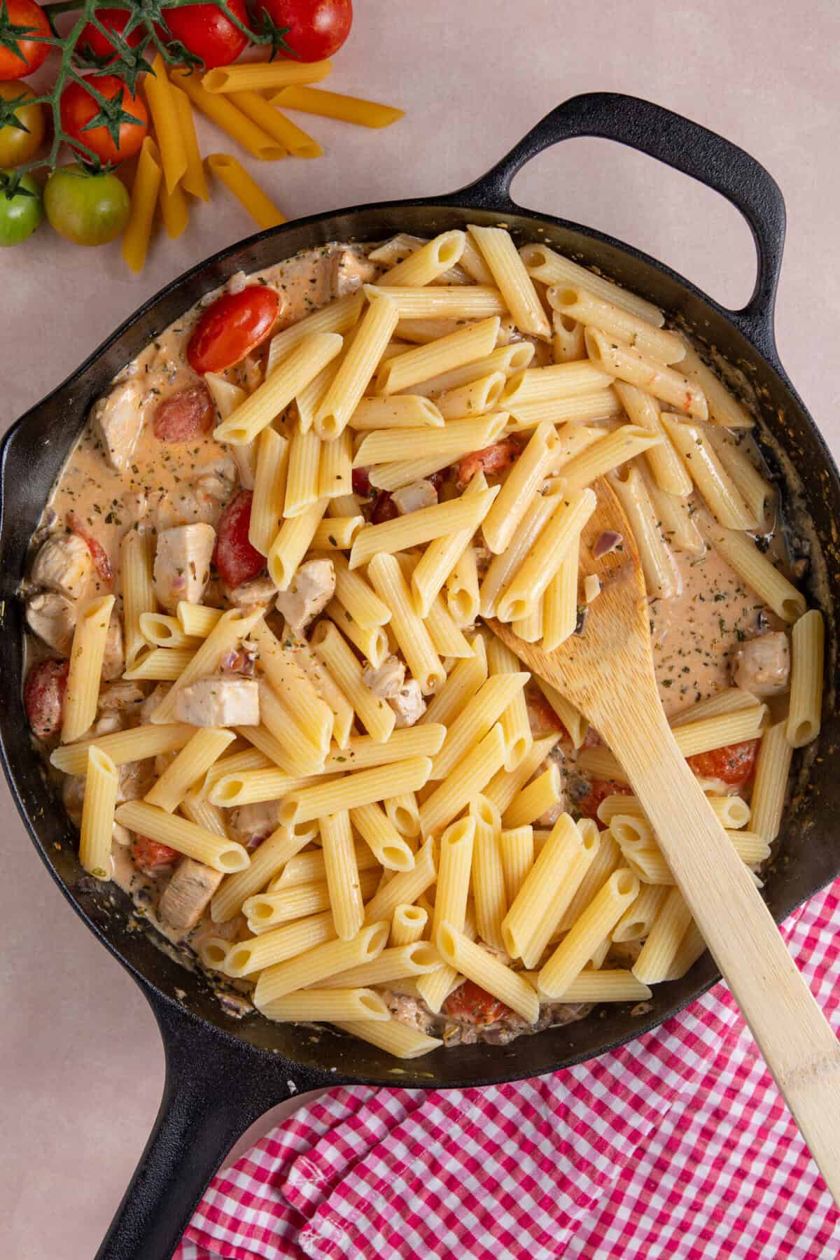 Process shot of creamy chicken tomato recipe showing the cooked pasta and cream added to finish the dish.