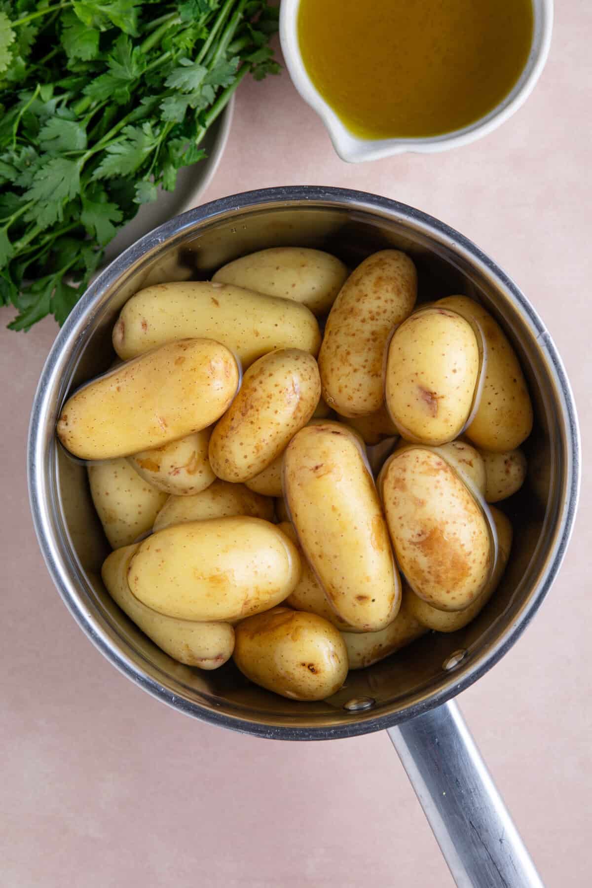 Process shot of chimichurri smashed potatoes recipe showing a pan of potatoes in water.