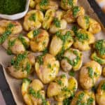 A tray of smashed potatoes drizzled with homemade chimichurri sauce.
