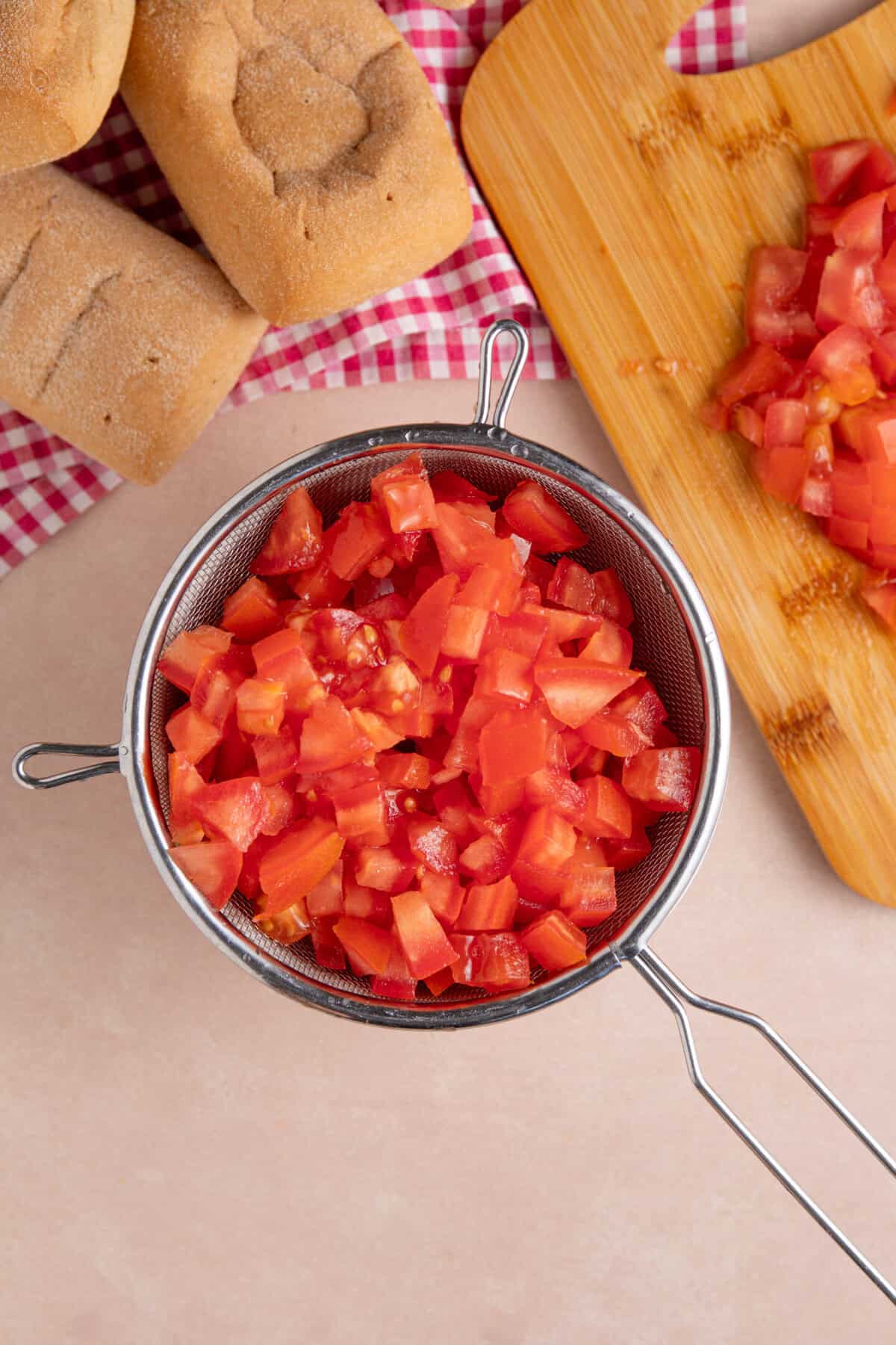 Process shot for gluten free bruschetta showing chopped tomatoes in a sieve.