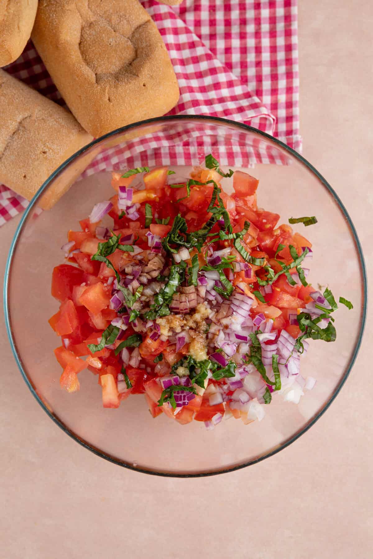 Process shot for gluten free bruschetta showing the tomatoes, coriander, garlic and red onion in a glass bowl.