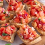 A board of gluten free bruschetta topped with tomatoes.